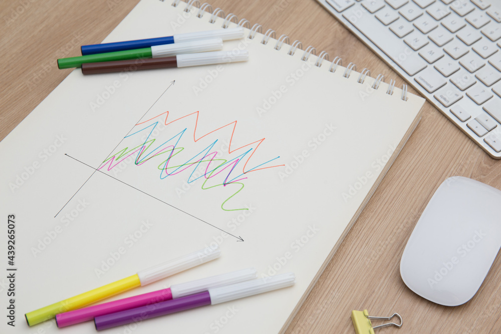Drawing a graph of growth in a notebook on your desk at home.Wooden work table Drawing a graph of growth in a notebook on your desk at home.Wooden work table
