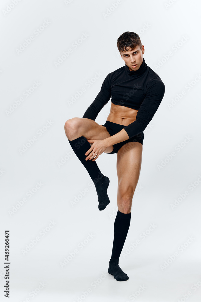 a man athlete in shorts, a sweater and socks raised his leg up