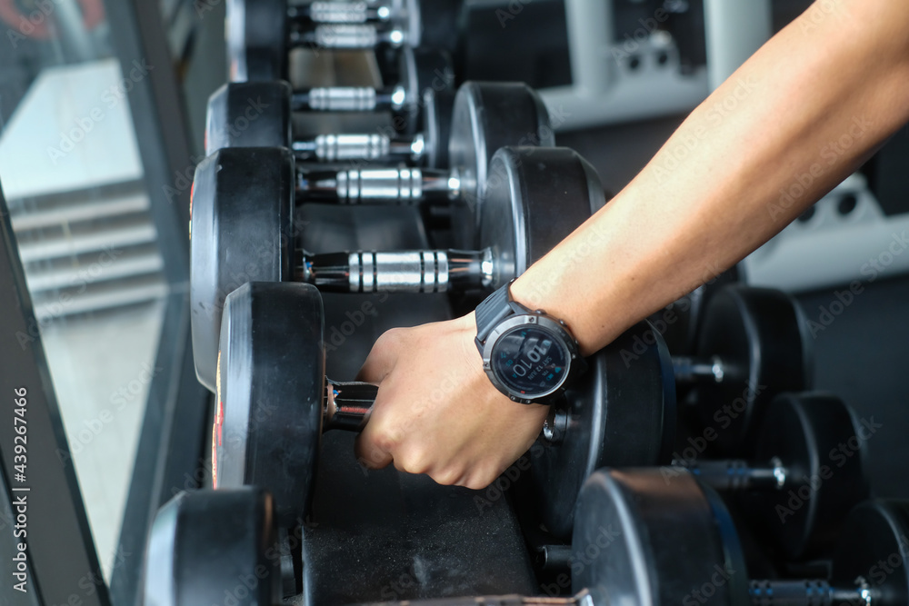 Strong well built bodybuilder lifting dumbbell weights getting ready for exercise in fitness Strong well built bodybuilder lifting dumbbell weights getting ready for exercise in fitness