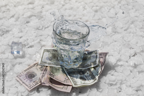 glass full of water stands on dollars and on large pieces of salt, water splash