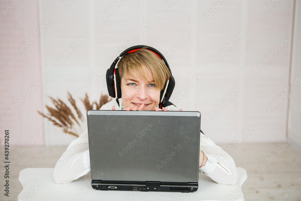 woman works at a laptop, wearing headphones and a microphone for communication woman works at a laptop, wearing headphones and a microphone for communication