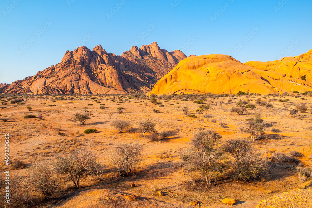 Naklejka premium Pontok Mountains near Spitzkoppe. Red vivid granite rock formation in Namib Desert at sunset time, Namibia, Africa