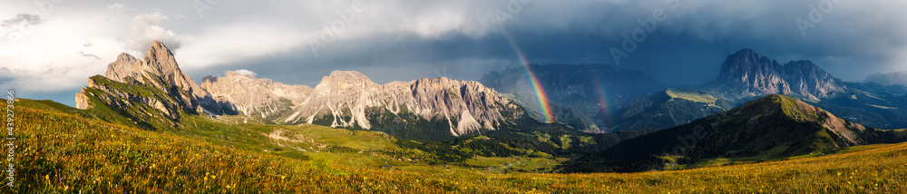 Panoramic view of idyllic mountain scenery in the Dolomites Alps with Majestic Peaks, Overcast sky and Rainbow. Odle mountain range, Seceda and Furchetta peak. Val Gardena in Dolomites. Italy.