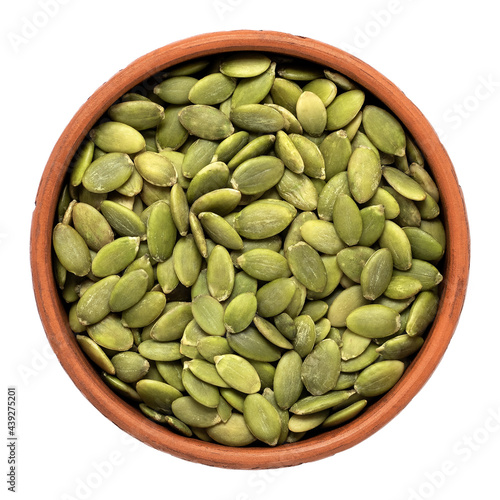 Pumpkin seeds in a bowl isolated on white background. Top view.
