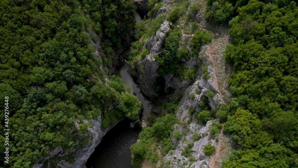 Drone flight over a picturesque river canyon, high sheer cliffs overgrown with greenery