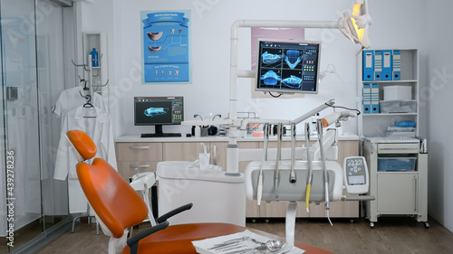 Empty modern orthodontist stomatology hospital bright office with nobody in it equipped with tooth intruments ready for dental healthcare. Revealing shot of tooth xray imanges on display © DC Studio