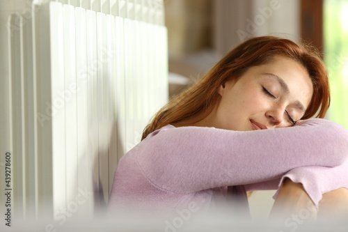 Relaxed woman sleeping leaning on radiator at home