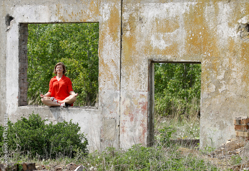 A beautiful woman sitting in a lotus pose in an old building photo