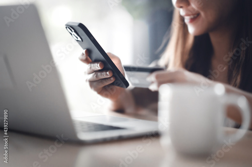 Online payment, Closeup Woman hands holding a credit card and using smart phone and laptop for online shopping