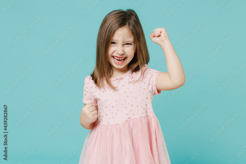 Little fun cute kid girl 5-6 years old wears pink dress doing winner gesture say yes isolated on pastel blue color background child studio portrait. Mother's Day love family people lifestyle concept. Little fun cute kid girl 5-6 years old wears pink dress doing winner gesture say yes isolated on pastel blue color background child studio portrait. Mother's Day love family people lifestyle concept.