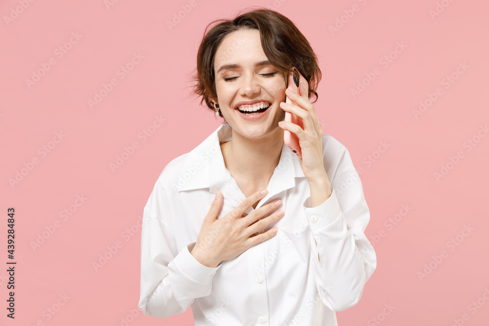 Happy laughing cheerful young employee business woman corporate lawyer in classic formal white shirt work in office talk by mobile cell phone isolated on pastel pink color background studio portrait. Happy laughing cheerful young employee business woman corporate lawyer in classic formal white shirt work in office talk by mobile cell phone isolated on pastel pink color background studio portrait.