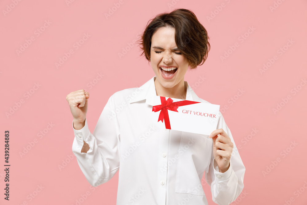 Happy fun young employee business secretary woman 20s corporate lawyer in classic formal white shirt work in office hold gift voucher flyer mock up isolated on pastel pink background studio portrait. Happy fun young employee business secretary woman 20s corporate lawyer in classic formal white shirt work in office hold gift voucher flyer mock up isolated on pastel pink background studio portrait.