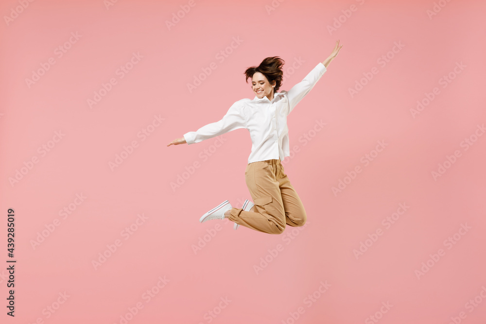 Full length overjoyed young successful employee business woman corporate lawyer in classic formal white shirt work in office jump high with outstretched hands fly isolated on pastel pink background