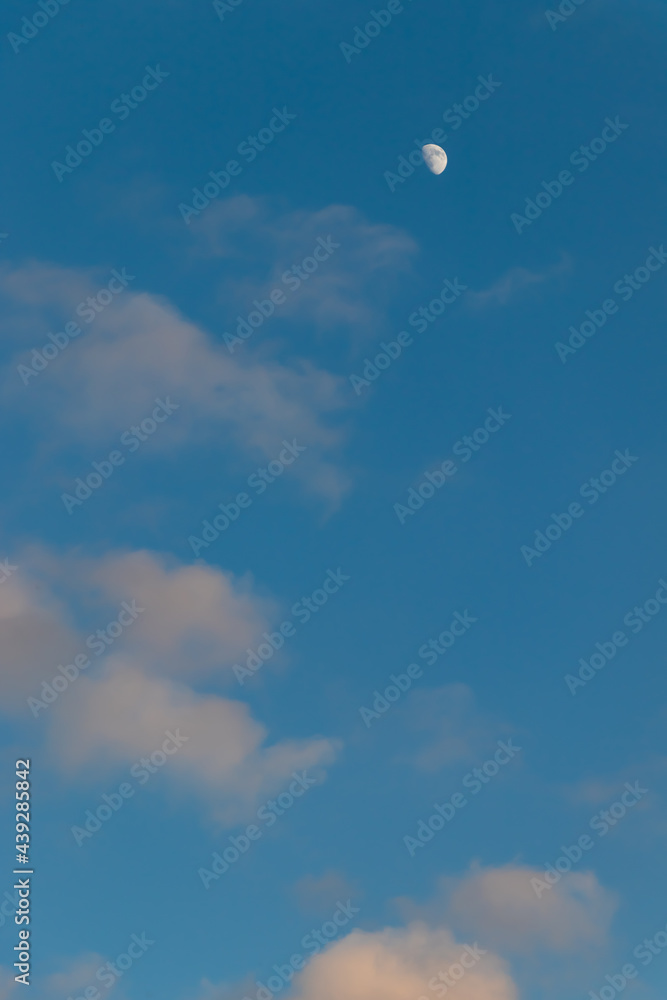 Blue sky with white gray clouds and bright white moon silhouette Blue sky with white gray clouds and bright white moon silhouette
