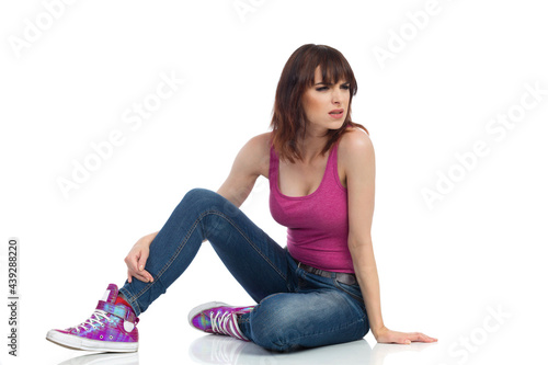 Young Woman Is Sitting On Floor, Narrowing Eyes And Looking Away.