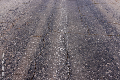 The texture of the asphalt in the cracks, hard crumbling asphalt in the village.