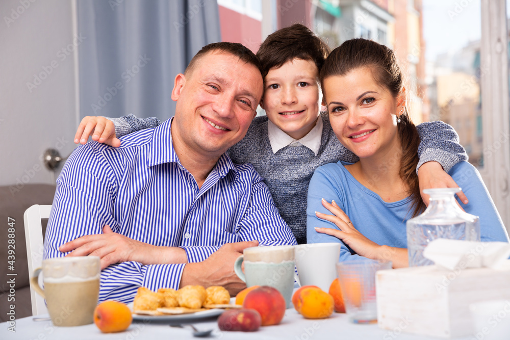 Portrait of happy loving family posing together during breakfast at home table