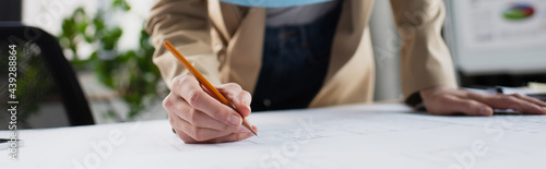 partial view of engineer drawing blueprint in office, banner