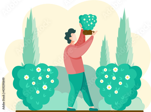 Guy gardening plants on backyard, flowers on beautiful bush, enjoying flowering in spring garden. Gardener standing wth bouquet in hands. Organic horticulture. worker is engaged in gardening