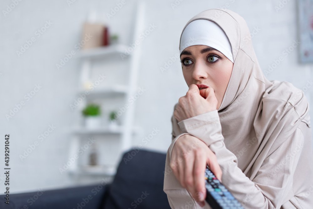 nervous arabian woman holding hand near face while watching tv at home nervous arabian woman holding hand near face while watching tv at home