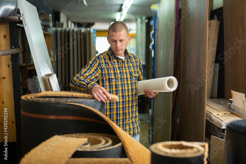 Man consumer choosing carpet in a hardware store