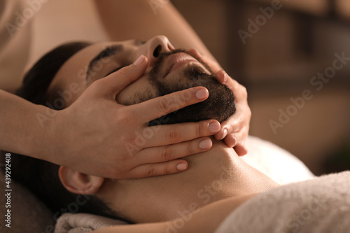 Young man receiving facial massage in beauty salon  closeup