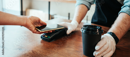 Mobile and safety wireless payment using cell phone and bank terminal. Coffee small business, close-up
