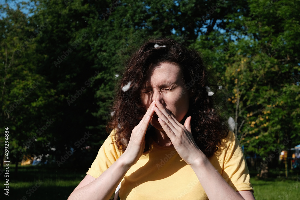 Girl sneezes because of the poplar fluff. Allergic reaction to poplar fluff Girl sneezes because of the poplar fluff. Allergic reaction to poplar fluff