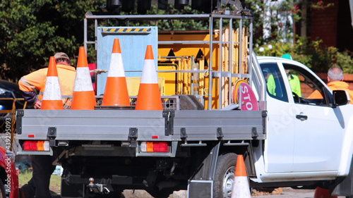 Road work company ute loaded with signs and orange road cones. Road workers are in the background photo
