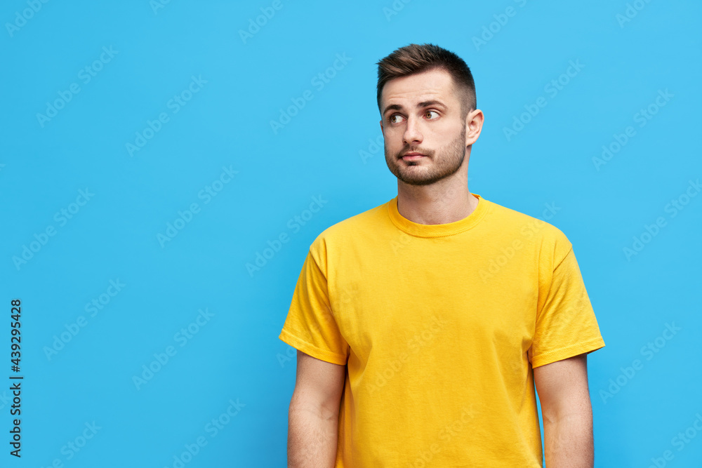 Doubtful thoughtful man looking aside to copy space over blue background Doubtful thoughtful man looking aside to copy space over blue background