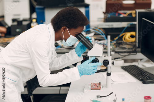 Scientist african american woman working in laboratory with electronic tech instruments and microscope. Research and development of electronic devices by color black woman.