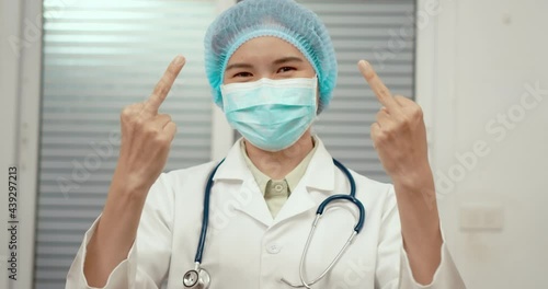 Doctor woman shows the middle finger. Bad expression. Hand gesture Fuck you. Rude attitude. Doctor's face in a protective mask and cap of a surgeon. Not a polite employee.