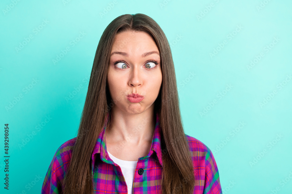 Portrait of attractive funky girl wearing checked shirt grimacing fooling isolated over bright teal green color background Portrait of attractive funky girl wearing checked shirt grimacing fooling isolated over bright teal green color background