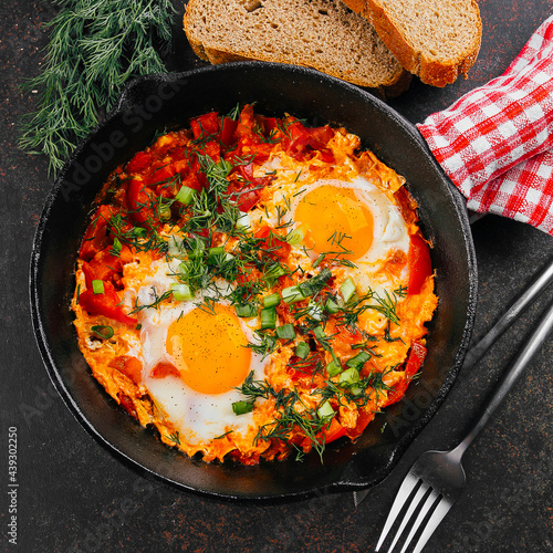 Top view of shakshuka with bread. Dish with eggs, tomato and dill in iron pan. Keto food diet photo