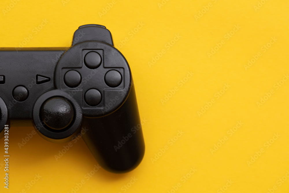 Black video game controller on a bright yellow background Black video game controller on a bright yellow background