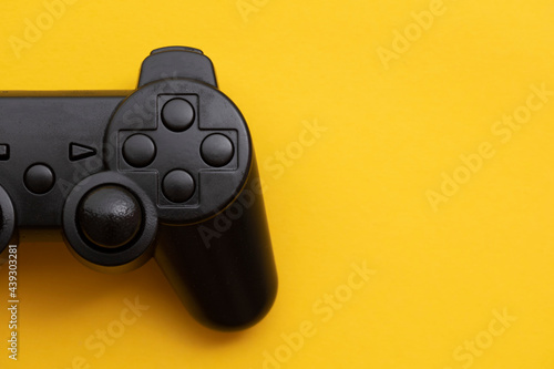 Black video game controller on a bright yellow background