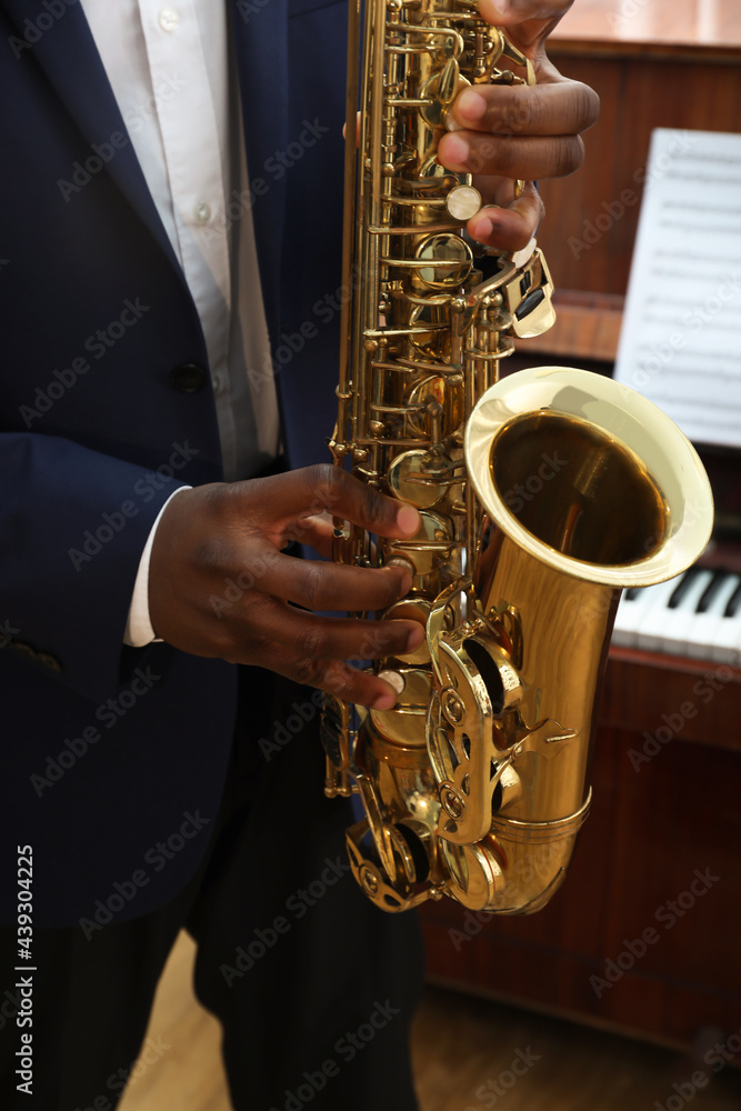 Obraz premium African-American man playing saxophone indoors, closeup. Talented musician