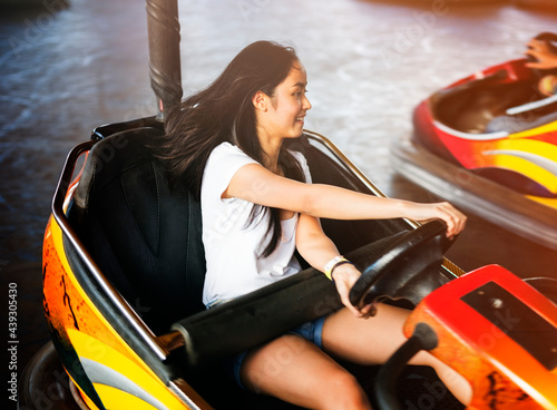 Young adult woman playing in bumper car at amusement park photo