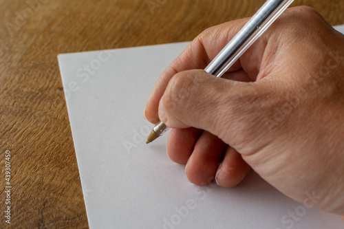 Male hand with pen writing on a blank sheet of paper