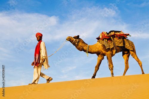Obraz na plátne Indian man walking through the desert with his camel