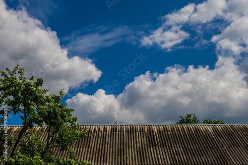 roof of the house and white clouds against the blue sky.