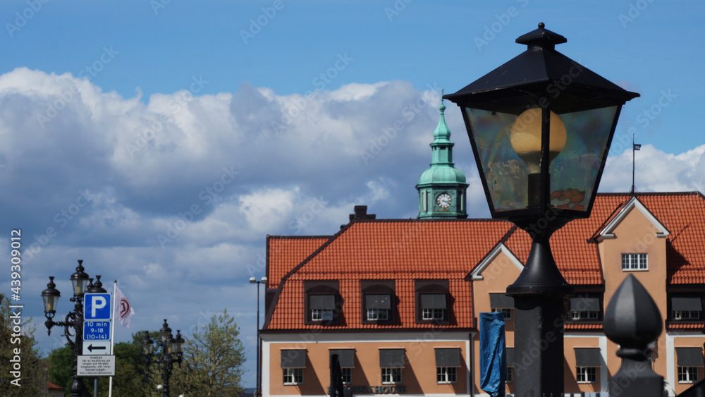 close up view of traditional street lantern with background of traditional buildings and bell tower clock, Karlskrona, Sweden