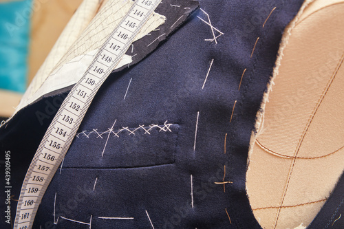 Sewn chest pocket on semi-ready suit jacket. Suit tailoring in process of custom-made jacket. Bespoke suit tailoring in tailor workshop. Working on a made-to-measure suit jacket