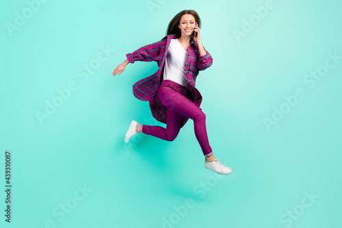 Profile full length photo of cool young lady go talk telephone wear shirt trousers isolated on vivid teal color background
