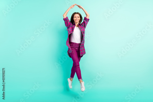 Full length body size view of attractive cheery fit girl jumping posing showing roof isolated over bright teal color background