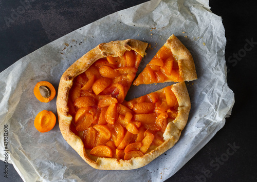 Delicious homemade French galette with ripe sweet apricots on a smooth dark background. Flat lay. Fresh handmade vegan food. Sweet pastries with apricots.
