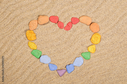 Multicolored stones laid out in the shape of a heart on the sand