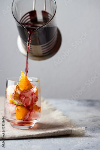 Sangria, Spanish summer drink pouring into the glass with ice and fruit Refresment beverage concept. photo