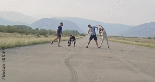 group of sporty people stretching after morning jogging workout photo