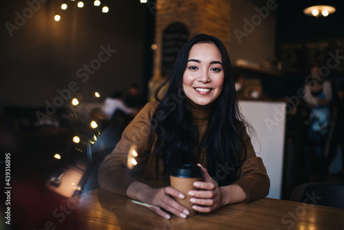 Smiling young Asian lady drinking hot coffee in cafeteria © BullRun